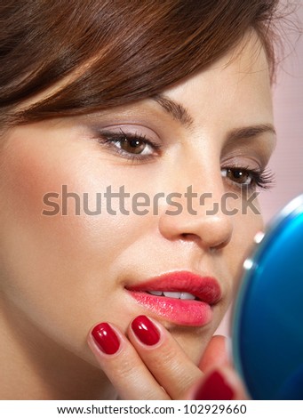 beautiful woman smartens up in front of compact mirror