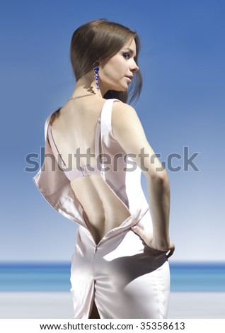back of beautiful young fiance in pink dress on shore