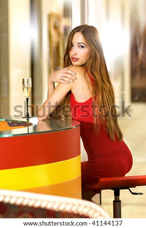 beautiful single woman in red dress with glass of champagne