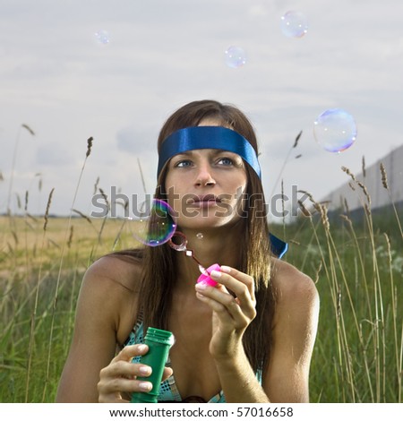 thoughtful young woman blowing soap bubbles in summer day
