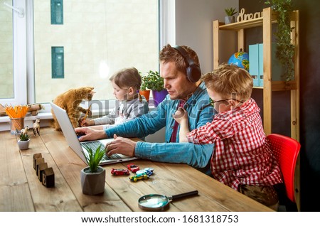 Photo of Work from home. Man works on laptop with children playing around. Family together with pet cat on table
