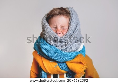The sick child covered his neck with scarves. School child boy with allergic. Flu season. Kid with cold rhinitis, get cold. Back to school. Child catch cold. 