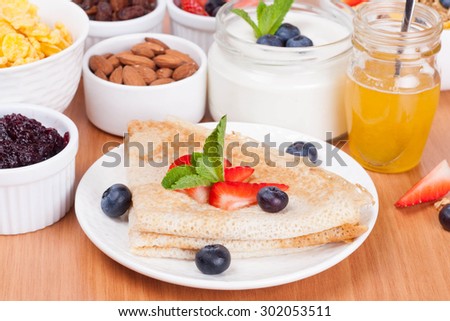 delicious breakfast - crepes with fresh berries and honey, close-up