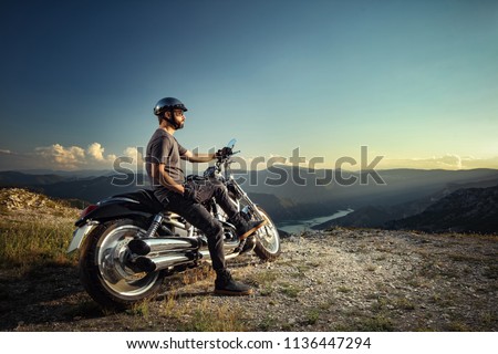 Foto Bild Mountainbiker aufgestützt auf Fahrradlenker blickt in die Ferne.