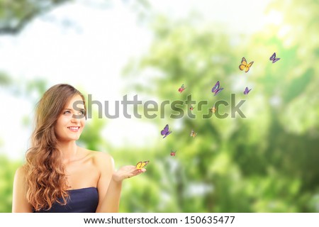 Beautiful female with a butterfly on her hand, posing in a park