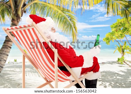 Santa Claus on a beach chair drinking beer and enjoying on a sunny day, on a tropical beach