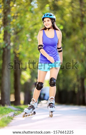 Full length portrait a young smiling female on rollers skating in a park