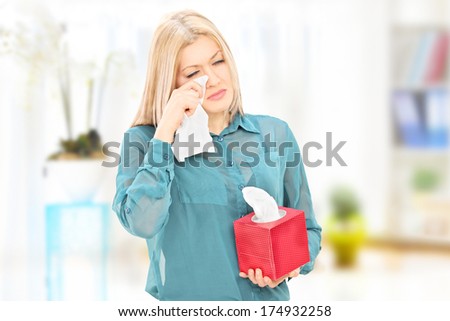 Sad young woman wiping her eyes from crying at home