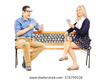 Young couple playing cards seated on wooden bench isolated on white background