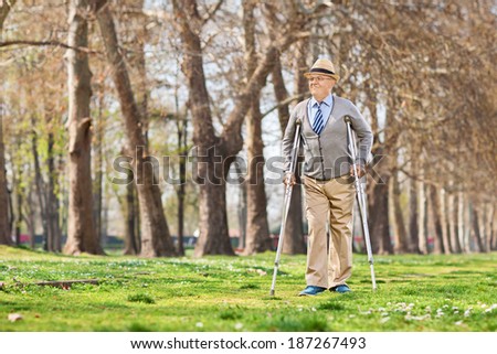 Senior gentleman walking with crutches in park