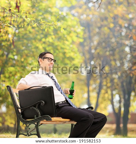 Businessman taking a break in park with a beer shot with tilt and shift lens