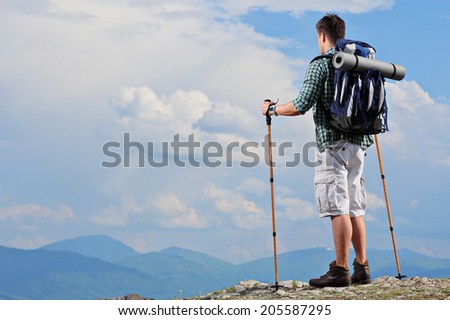 Male hiker standing on a mountain top and holding hiking poles