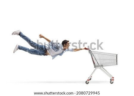 Full length shot of a casual guy man flying and holding an empty shopping cart isolated on white background 商業照片 © 