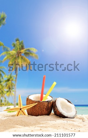 Creative cocktail in a coconut cup on a tropical beach on a hot summer day