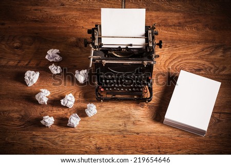 Retro typewriter on a wooden desk and a stack of paper beside it
