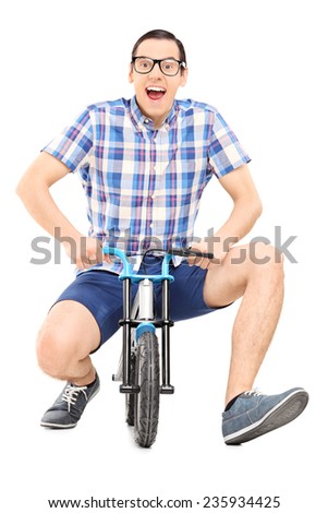 Silly young man riding a small childish bike isolated on white background