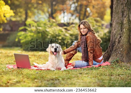 Beautiful girl sitting with her dog in park on blanket