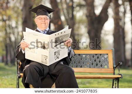 Mature college professor reading the news in park seated on a bench