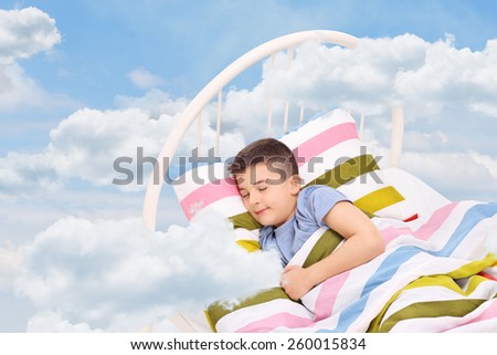 Cute little boy sleeping on a bed in the clouds