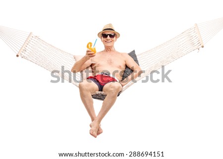 Carefree senior in red swim trunks lying in a hammock and drinking a delicious orange cocktail isolated on white background