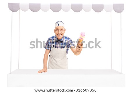 Senior ice cream vendor standing behind a stall and giving an ice cream towards the camera isolated on white background