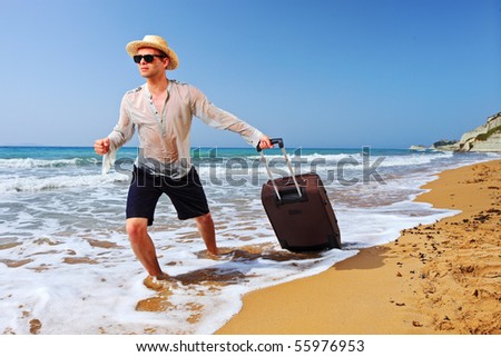 A tourist carrying a suitcase at the beach Peroulades at Corfu island, Greece