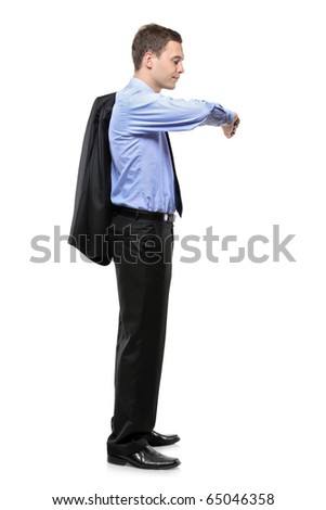 Full length portrait of a man in a business suit standing and looking at his wrist watch isolated on white background
