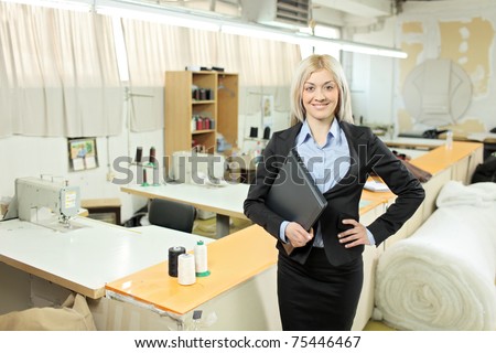 Female owner of a small business standing inside a textile factory holding a laptop computer in her hand