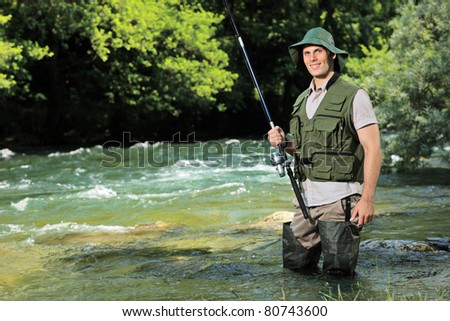 A young fisherman posing with fishing pole in his hand on a river Treska, Macedonia