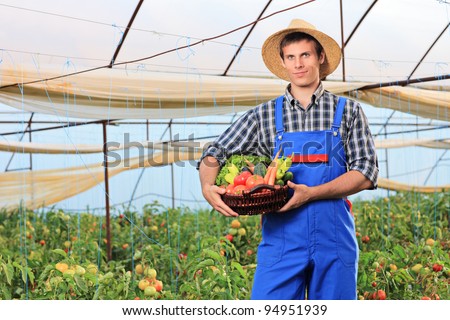 A smiling gardener holding a basket full of vegetables in a garden