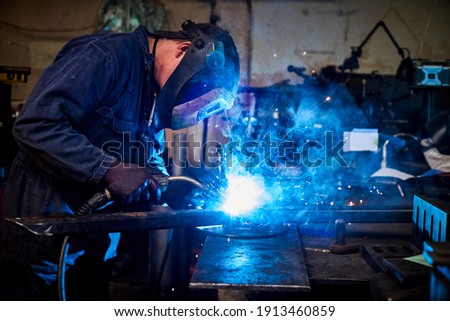 Similar – Image, Stock Photo welder is welding metal part in garage. with protective mask,