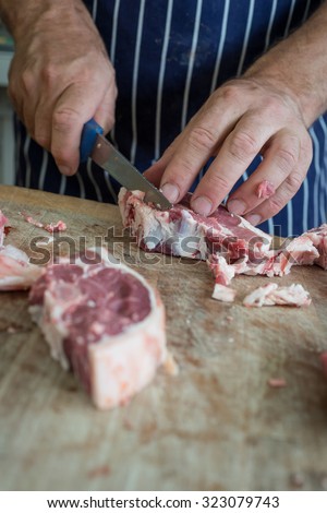 Friendly man preparing raw meat at the butchers