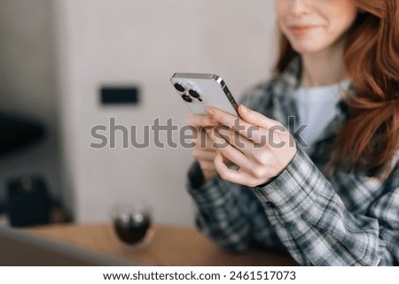 Foto Bild nicht erkennbare junge Frau zu Hause, die ein Mobiltelefon am Fenster benutzt