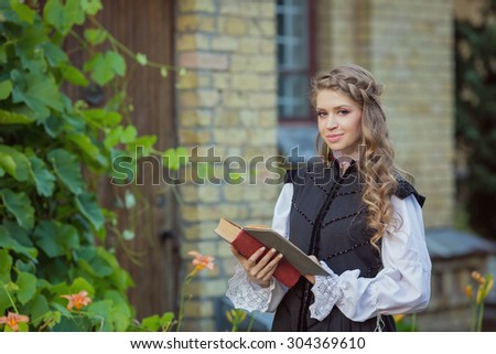 Beautiful girl in historical black dress with book