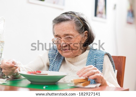 Old woman eating her lunch at home