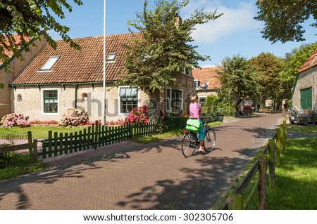 AMELAND, NETHERLANDS - AUGUST 14, 2004: Street scene with woman on bicycle in  historical town Hollum on West Frisian island Ameland, Netherlands