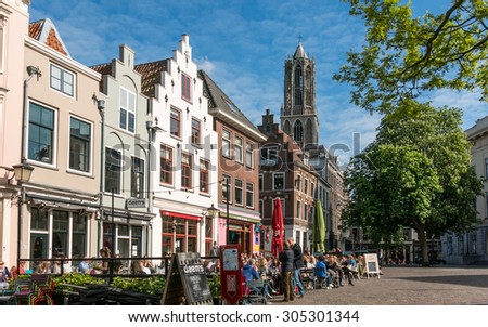 UTRECHT, NETHERLANDS - MAY 21, 2015: Cafes and facades of old houses on Minrebroederstraat and the tower of Dom Church in the city of Utrecht, Netherlands