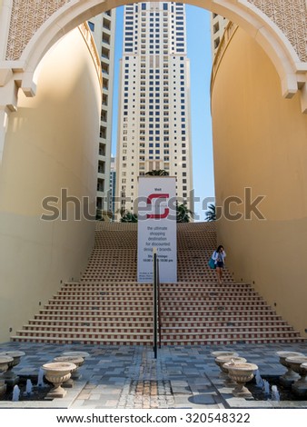 DUBAI, UNITED ARAB EMIRATES - JAN 25, 2014: Woman walking down stairs of shopping centre The Walk in the Marina district of Dubai, United Arab Emirates
