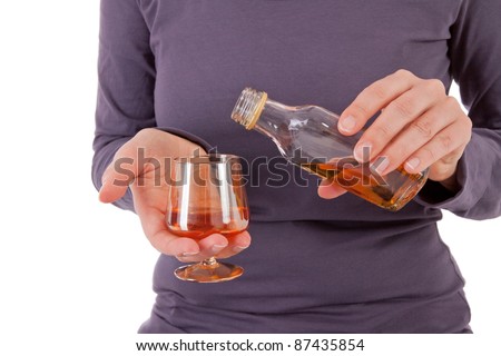 A young woman is pouring herself a glass of hard liquor