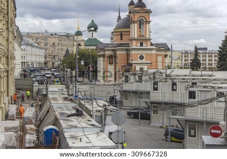 MOSCOW, RUSSIA - AUGUST 17, 2015. Repair of streets Varvarka, view from above. Workers, building, wagons, equipment in the foreground. Street, cars, church in the background.
