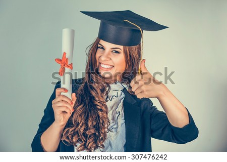 Portrait closeup beautiful smile latina graduate graduated student girl young woman in cap gown showing thumbs up holding diploma scroll isolated green background wall. Celebrating graduation ceremony