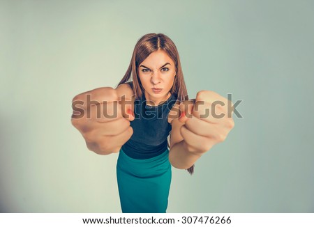 Closeup portrait angry young woman showing fists about to punch hit someone or to have nervous atomic breakdown isolated black background. Negative human emotions facial expression feelings attitude