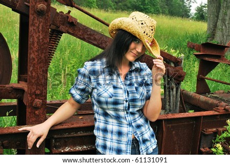 Country Girl tipping hat against farm rusted farm equipment/Young Country Girl