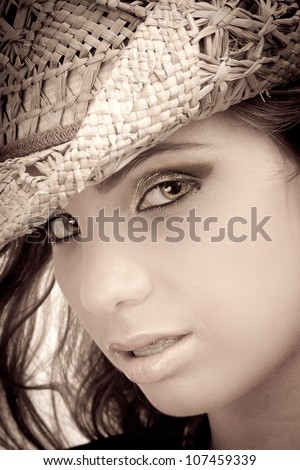 Close up of the face of a sexy young woman looking in a sensual manner. The girl is blonde and she is isolated on white background. Wearing a cowboy hat.
