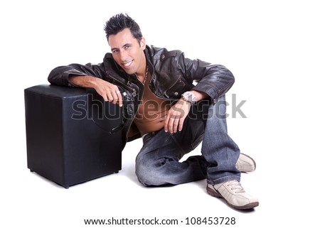 A sexy man looking to the camera, wearing a leather jacket. The guy is looking happy and smiling on a sexy manner. Good for concept of lifestyle and maleness.