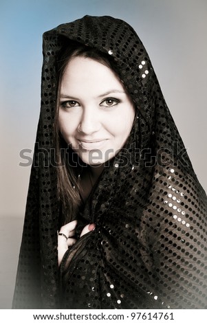 Beautiful woman  covering her face with a black hijab with beautiful bright spots on it.