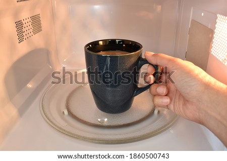 Cup of tea or coffee in microwave.  Concept of heating your drink in microwave.