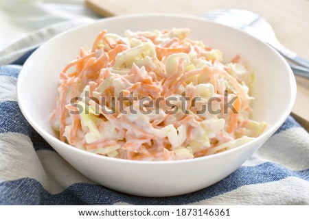 Coleslaw salad with carrot and cabbage on a white bowl.