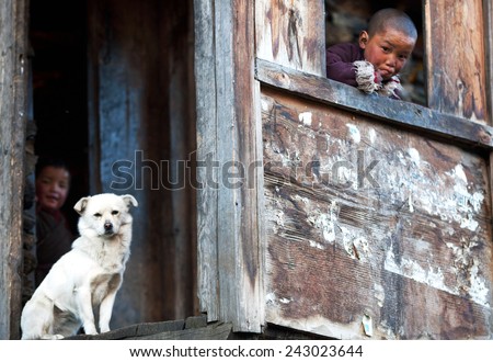 LHO, MANASLU CONSERVATION AREA, NEPAL - NOVEMBER 29: Tibetan boy Lapsang, 9, with white dog poses for a photo at him home on November 29, 2009 in Lho village, Tsum valley, Nepal
