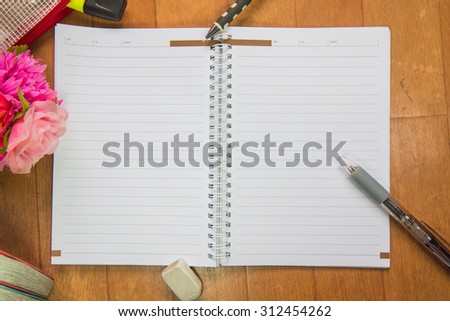 Blank space of notepad with supplies and flower. Top view with copy space